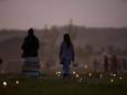 Vrouwen lopen door een veld. Vlaggen en lampjes markeren de plekken waar meer dan 750 ongemarkeerde graven werden ontdekt, bij de voormalige Marieval Indian Residential School in Saskatchewan.