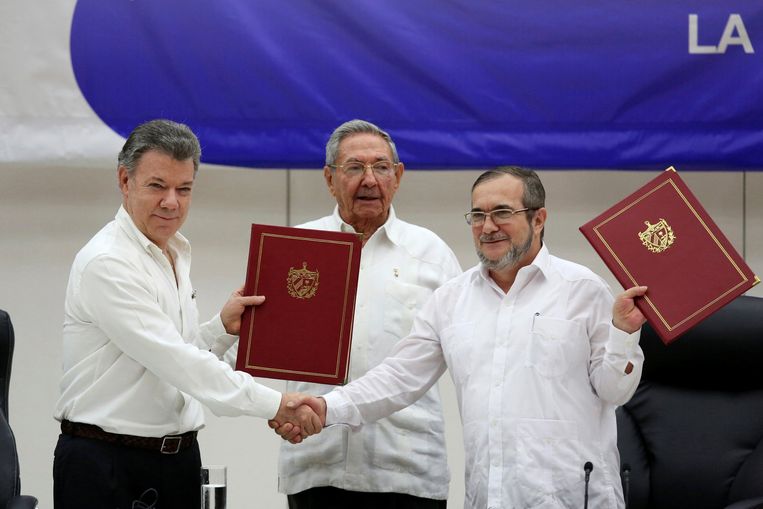 De Colombiaanse president Juan Manuel Santos schudt de hand van de FARC-leider Rodrigo Londono. Achter het duo staat de Cubaanse president Raul Castro. Beeld reuters