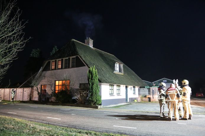 Brandweerlieden aan het werk bij de schoorsteenbrand in Holten.
