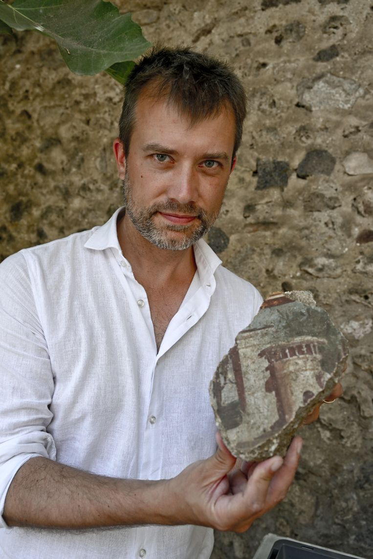 Gabriel Zuchtriegel, directeur van het archeologisch park Pompeiï, met een stuk van een gedecoreerde vloer uit een huis dat vermoedelijk al bij een aardbeving in het jaar 62 met de grond gelijk werd gemaakt. Beeld ANP / EPA