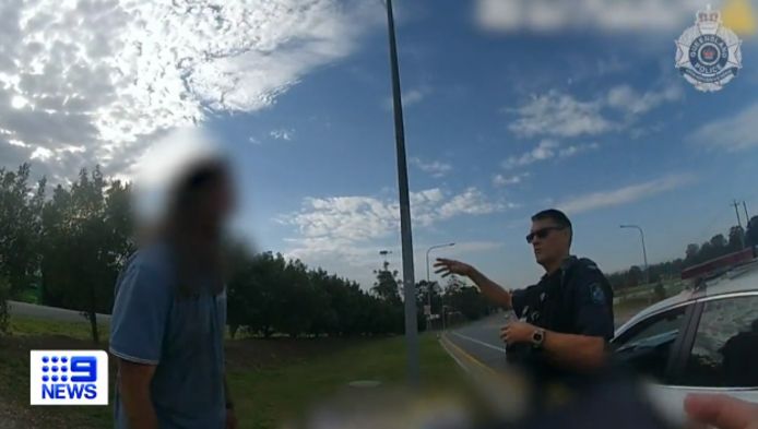 De dronken Australiër in gesprek met een verbaasde politieman, nadat hij werd ontdekt in het onderstel van de vrachtwagen.