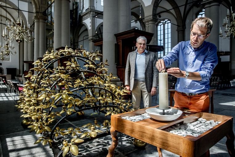Tim Vreugdenhil, stadspredikant steekt in de Amsterdamse Westerkerk een kaarsje op in het bijzijn van dominee Bas van der Graaf.  Beeld Jean-Pierre Jans