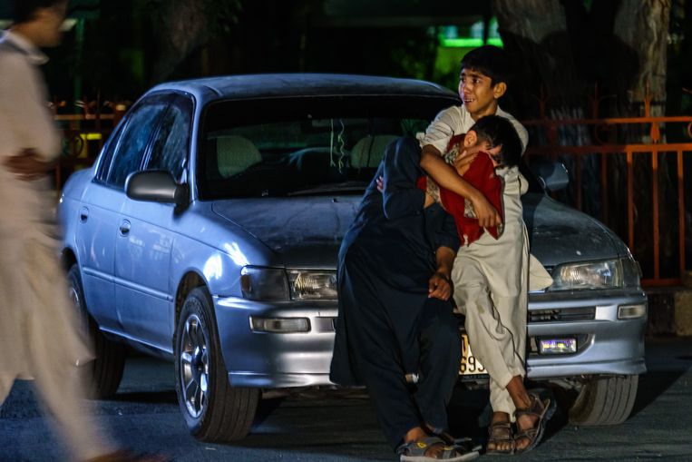 Twee jongens omhelzen elkaar na de aanslagen in Kabul donderdagmiddag. Beeld Los Angeles Times via Getty Imag