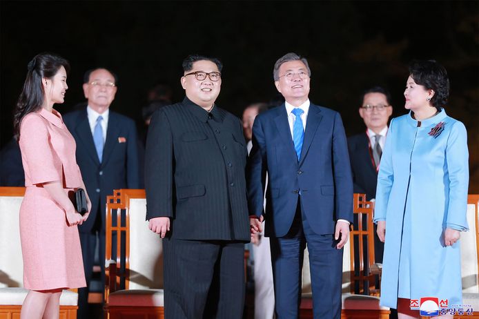 Kim en Mood hand in hand bij de slotceremonie, geflankeerd door hun vrouwen Ri Sol-ju (links) en  Kim Jung-sook.