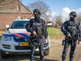 Zwaarbewapende politiemensen bewaken het terrein aan de Heitrak in Neerkant waar in februari 2021 een draaiend drugslab werd gevonden van de Eindhovense drugsbende.