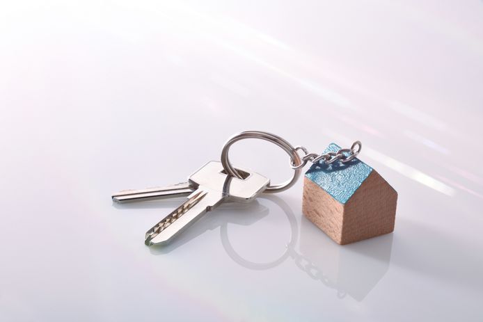 Keys with a house-shaped keyring on a white methacrylate table of a real estate agent