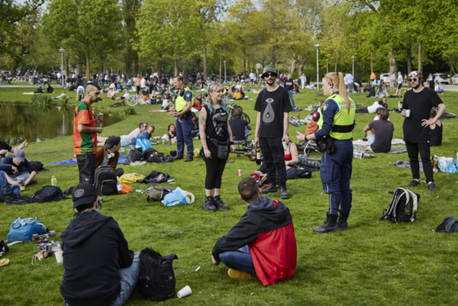 Handhavers wijzen bezoekers van het Vondelpark in Amsterdam erop dat ze zich moeten houden aan de anderhalvemeterregels.  Beeld Getty Images