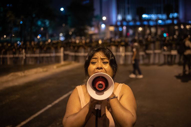 Een betoger spreekt zaterdag in Lima mededemonstranten toe, met achter haar een politiekordon. Beeld Nicola Zolin voor de Volkskrant