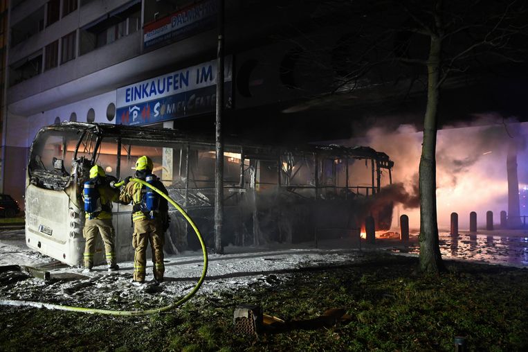 Brandweerlieden blussen een bus die in brand was gestoken op oudejaarsnacht in Berlijn. Beeld AP