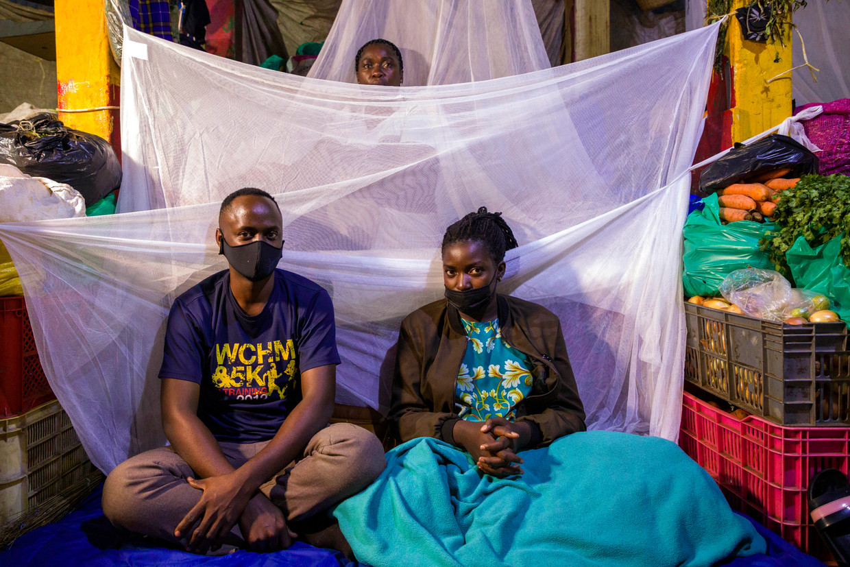 Abu Kikomeko (links), zijn zus Rebecca Nakyanzi en moeder Glades Ssebwira maken zich op om bij hun kraam op de markt van Nakasero in Kampala te gaan slapen. Vanwege nieuwe lockdownregels in Oeganda moeten marktkooplui 42 dagen lang of thuis of op hun markt blijven om te voorkomen dat ze het virus verspreiden.  Beeld Katumba Badru