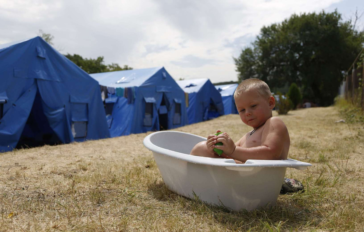 Een jongetje zit in bad in een tijdelijk vluchtelingenkamp in Oekraïne. Beeld afp
