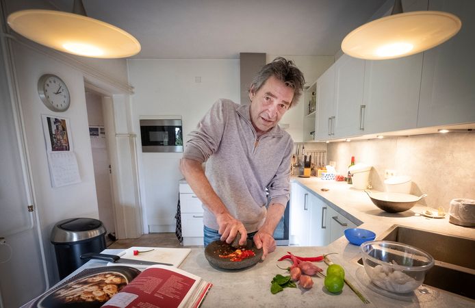 Flip Stoltenborgh met zijn kook- en reisboek aan werk in zijn keuken thuis.