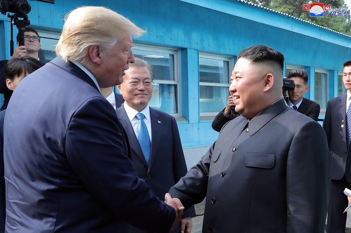 Trump en Kim Jong-un schudden elkaar de hand, de Zuid-Koreaanse president Moon Jae-in kijkt goedkeurend toe.