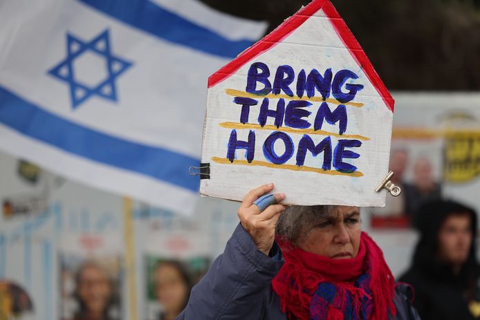 Archiefbeeld. Een vrouw houdt een protestbord omhoog met daarop "Bring them home", "Breng hen naar huis".