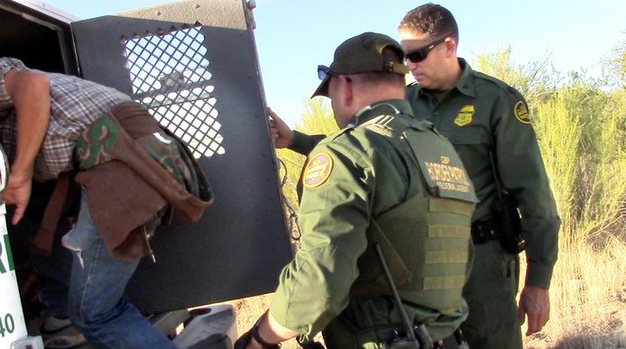 Amerikaanse grenswachter arresteren een migrant in de onherbergzame Sonoran Desert.