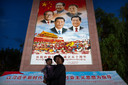 Un homme tient une fille dans ses bras alors qu'ils posent pour une photo devant une grande fresque représentant le président chinois Xi Jinping, en bas au centre, et d'autres dirigeants chinois sur une place publique au pied du palais du Potala à Lhassa, dans la région autonome du Tibet, dans l'ouest de la Chine. Le dirigeant chinois Xi Jinping a effectué une rare visite au Tibet alors que les autorités renforcent les contrôles sur la culture bouddhiste traditionnelle de la région himalayenne, accompagnés d'une accélération du développement économique et de la modernisation des infrastructures.