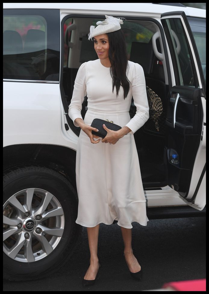 Meghan Markle in een loszittende, lange, witte jurk waarin haar armen bedekt zijn. Ze droeg deze outfit in Fiji.