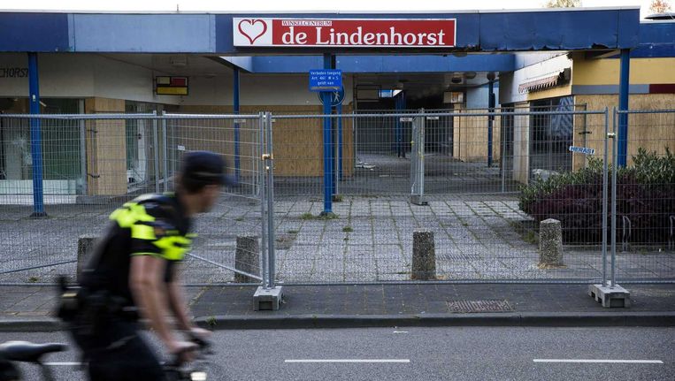 Een politieagent fietst langs het leegstaande winkelcentrum De Lindenhorst dat voor onrust zorgt in de Edese wijk Veldhuizen. Beeld anp