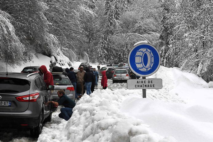 Gestrande toeristen monteren sneeuwkettingen op hun auto.