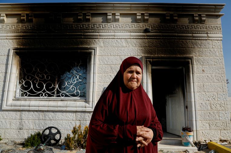 Een Palestijnse vrouw staat voor een huis dat zondag in brand werd gestoken.  Beeld Reuters