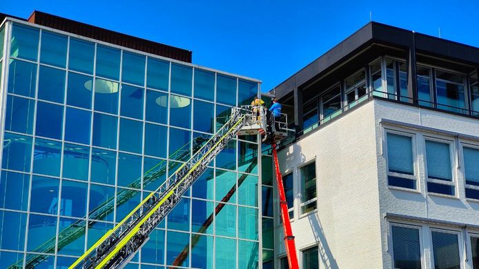 De vastgelopen hoogwerker in Enschede. De brandweer heeft er een man uit bevrijd die vast was komen zitten.