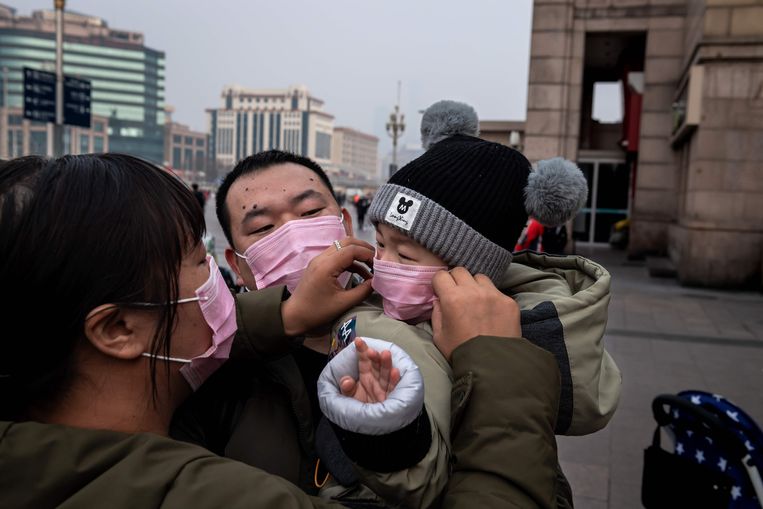 Een gezin neemt maandag de nodige voorzorgsmaatregelen in Wuhan. Beeld AFP