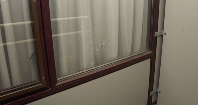 Een kogelgat in het raam van de studentenkamer.