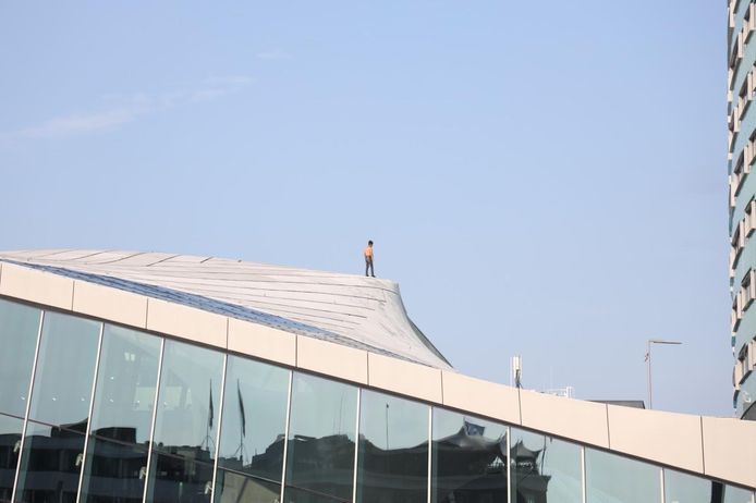 Een man staat op het dak van het centraal station in Arnhem.