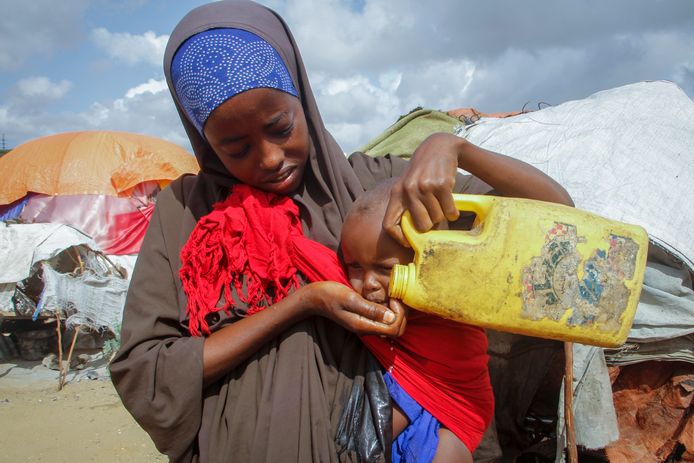 Une femme somalienne qui a fui les régions frappées par la sécheresse donne de l'eau à son bébé dans un récipient en plastique dans un camp pour personnes déplacées dans la banlieue de Mogadiscio, en Somalie, samedi 4 juin 2022.