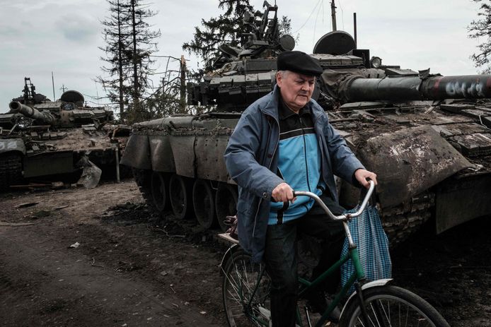 Een burger fietst voorbij achtergelaten Russische tanks in recent heroverd gebied nabij Charkiv. Beeld van 30 setember.