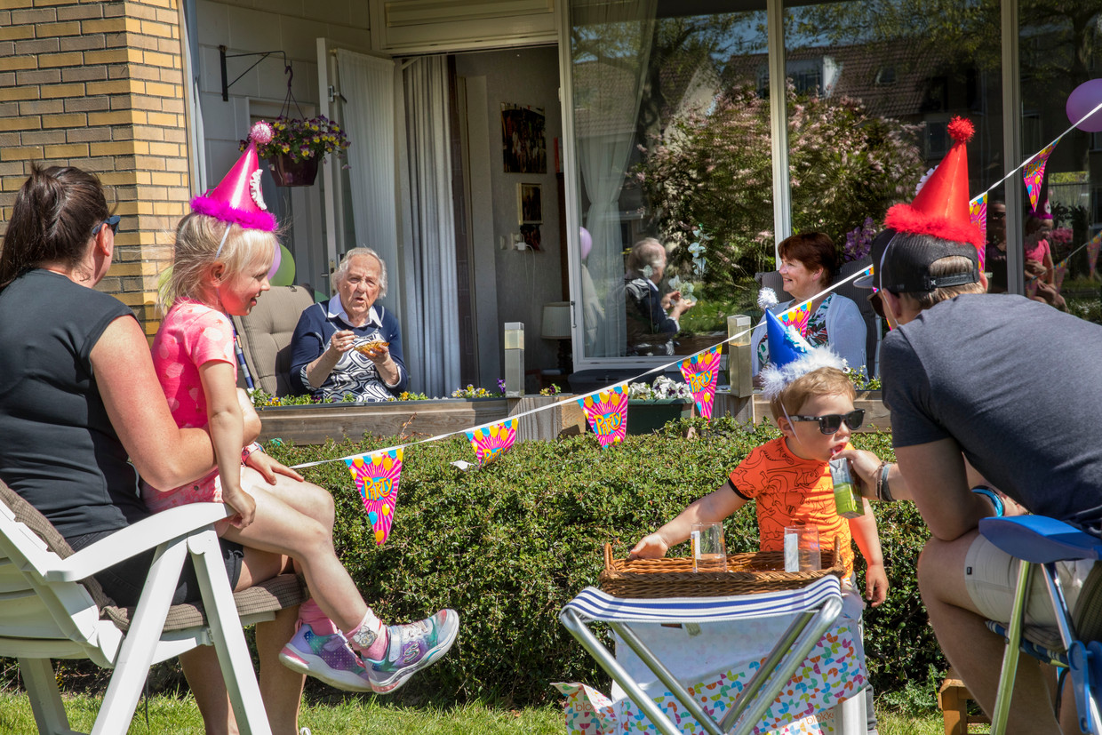Mevrouw Blom is 89 jaar geworden. Haar kleinkinderen en achterkleinkinderen blijven vanwege corona aan de andere kant van de heg.  Beeld Arie Kievit