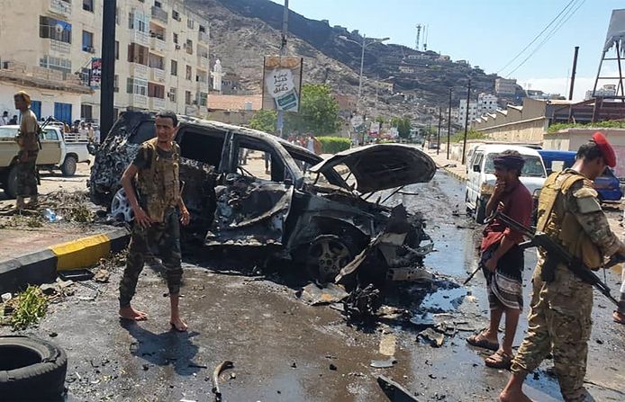 Jemenitische veiligheidstroepen verzamelen bij autowrakken na de bomaanslag in Aden.