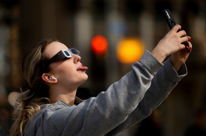 Een vrouw neemt een selfie terwijl ze naar de zonsverduistering kijkt op Parliament Hill in Ottawa, Ontario.