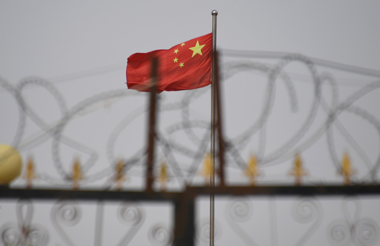 Op deze foto uit 2019 wappert de Chinese vlag achter de hekken van een kamp in Yangisar, in de westelijke regio Xinjiang. Volgens mensenrechtenorganisaties worden Oeigoeren daar vastgehouden.  Beeld AFP