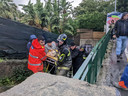 Italiaanse brandweermannen vervoeren een inwoner van  Casamicciola op een brancard.