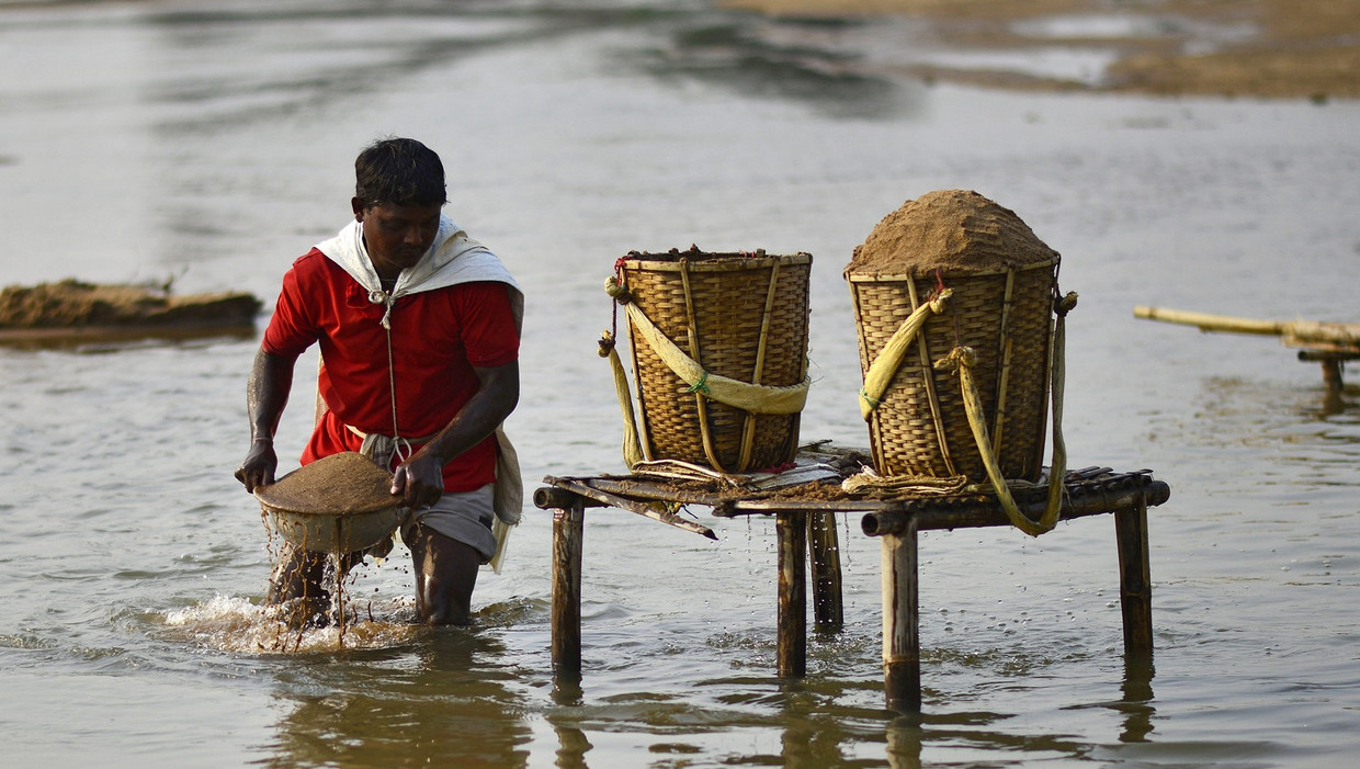 Indiase man verzamelt zand bestemd voor de bouwsector. Beeld epa