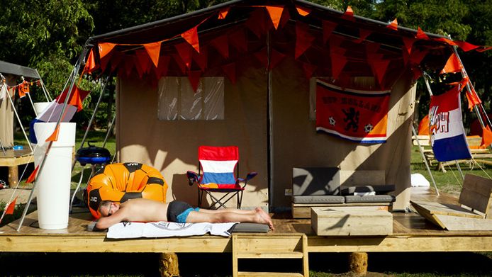 Een fan doet een dutje voor zijn tent op de Oranjecamping.
