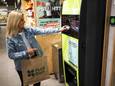 Een consument overhandigt symbolisch een blikje bij een inzamelpunt in een supermarkt tijdens de aftrap voor de invoering van 15 eurocent statiegeld op blikjes per 1 april.