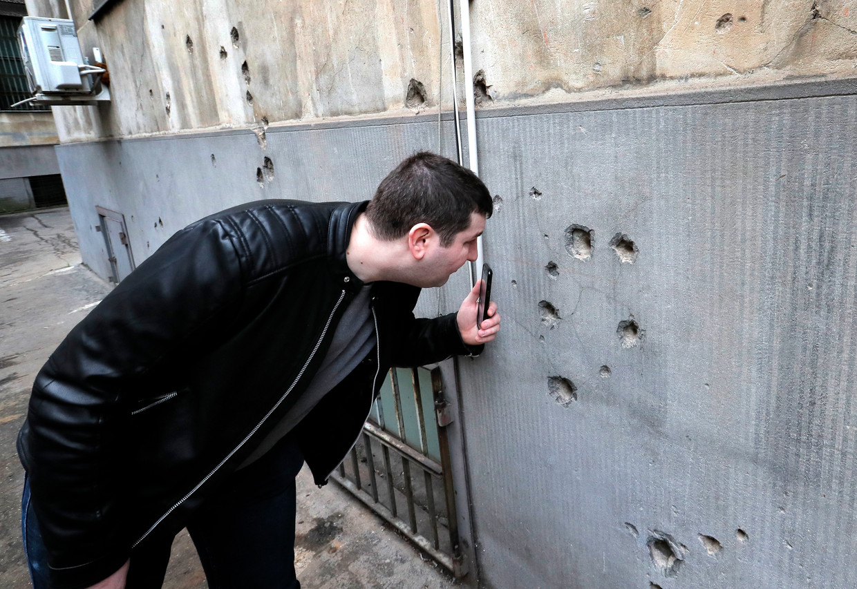 Een man bekijkt de kogelgaten op de binnenplaats van het voormalige ministerie van binnenlandse zaken in Boekarest, de voormalige thuisbasis van Ceausescu, tijdens een open dag. 