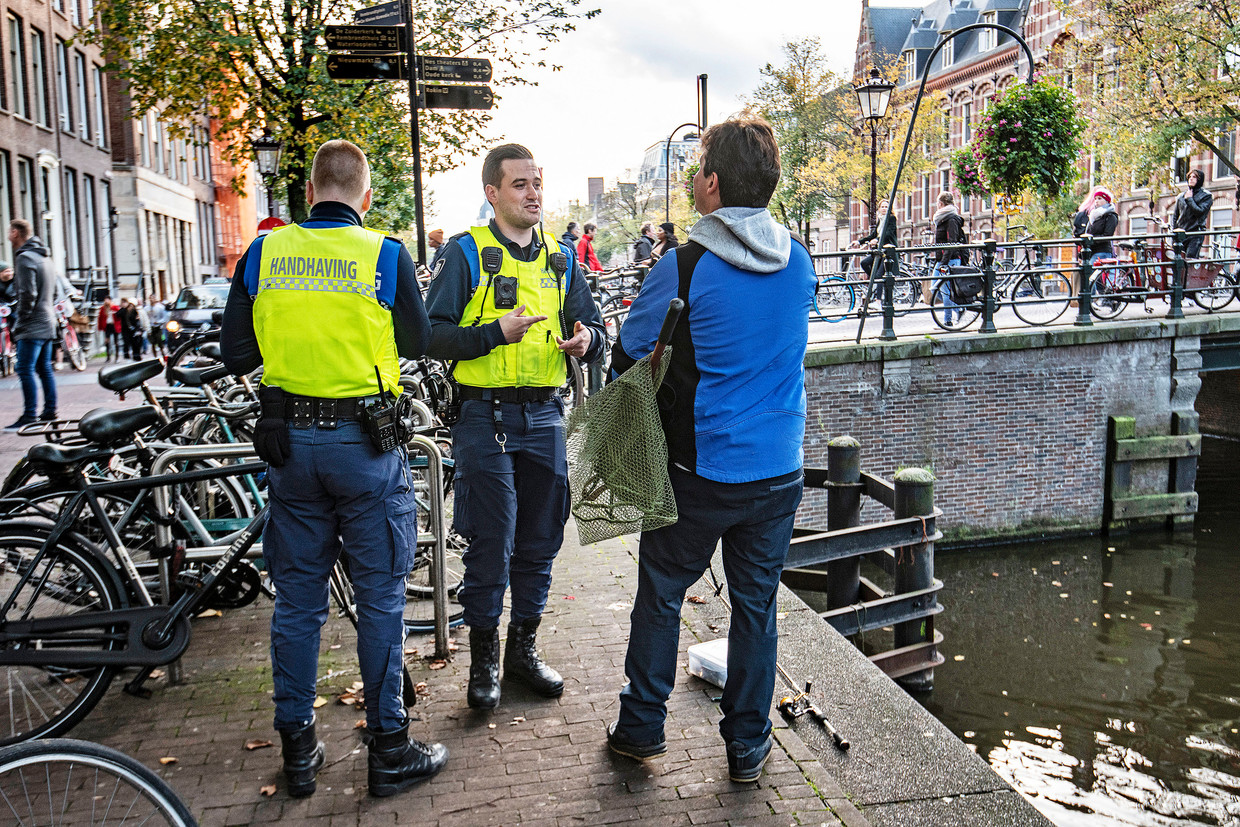 Boa's doen hun ronde in het centrum van Amsterdam. Een man wordt gecontroleerd op het bezit van een visakte.
 Beeld Guus Dubbelman / de Volkskrant
