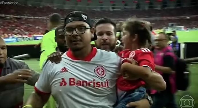 Internacional-fan gaat spelers van Caxias te lijf met jong meisje op de arm.