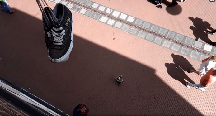 Jongens proberen met een magneet muntgeld uit het bakje van straatmuzikanten te vissen in Nijmegen.
