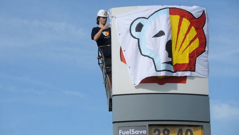 Een activist van Greenpeace bedekt het Shell-logo uit protest tegen de boringen in Alaska, in mei. Beeld AFP