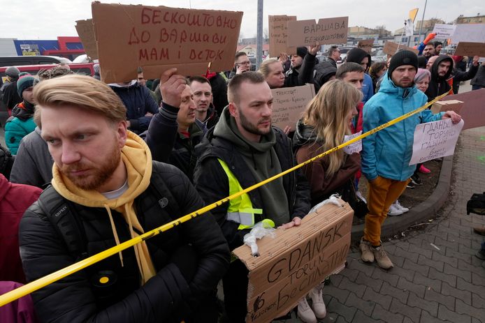 Mensen bieden met bordjes vervoer en slaapplekken aan bij de grens met Korczowa, Polen.