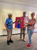 Jan Simons overhandigt een schilderij aan Van Hout Optiek, om hen attent te maken op het belang van een dementievriendelijk Meierijstad.