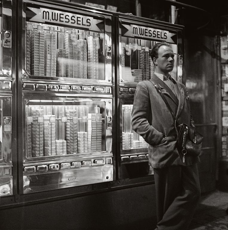 De geld­wisselaar die als enige de allereerste sigarettenautomaten van de stad mocht bedienen, 1954. Beeld Cor van Weele