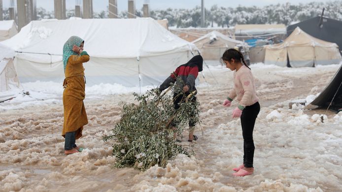 Kinderen met een tak om later op te branden voor de warmte. De meisjes staan met slippers in de sneeuw.