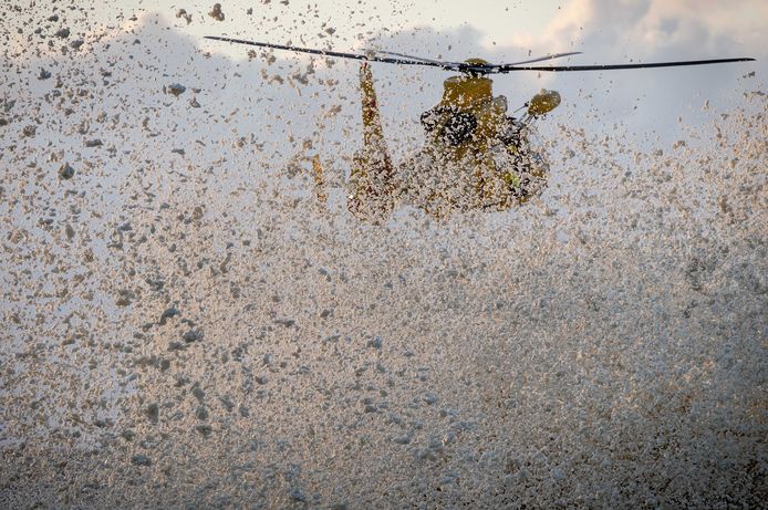 Een reddingshelikopter vliegt laag over de golven en doet het schuim opwaaien tijdens een zoekactie.
