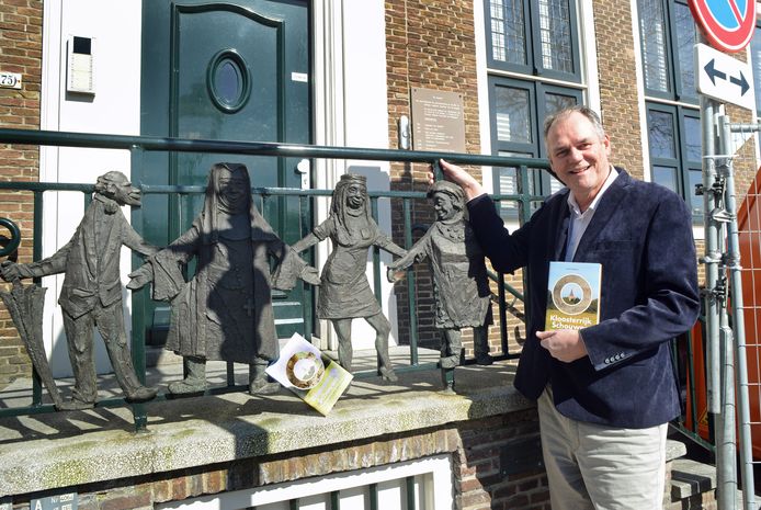 Auteur Henk Dalebout met zijn boek bij het door Ad Braat gemaakte bronzen reliëf van de Franciscanessen in de voormalige Corneliastichting in Zierikzee.