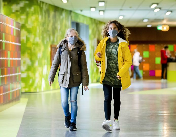 Leerlingen van een middelbare school dragen mondkapjes in de gang.
